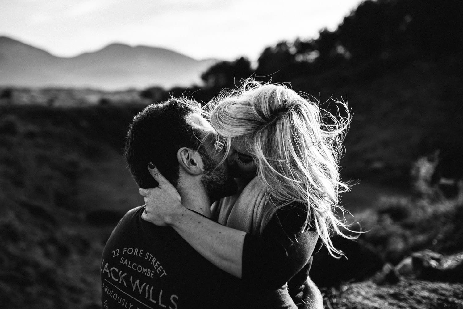 couple kissing black and white mountains in background