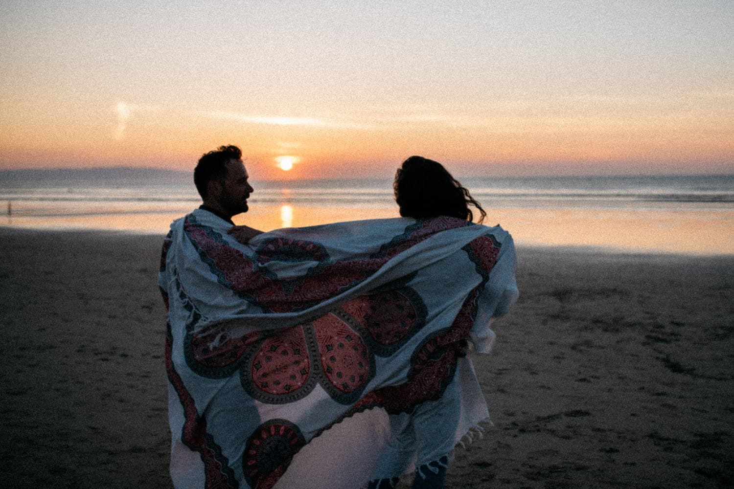 couple holding blanket on the beach