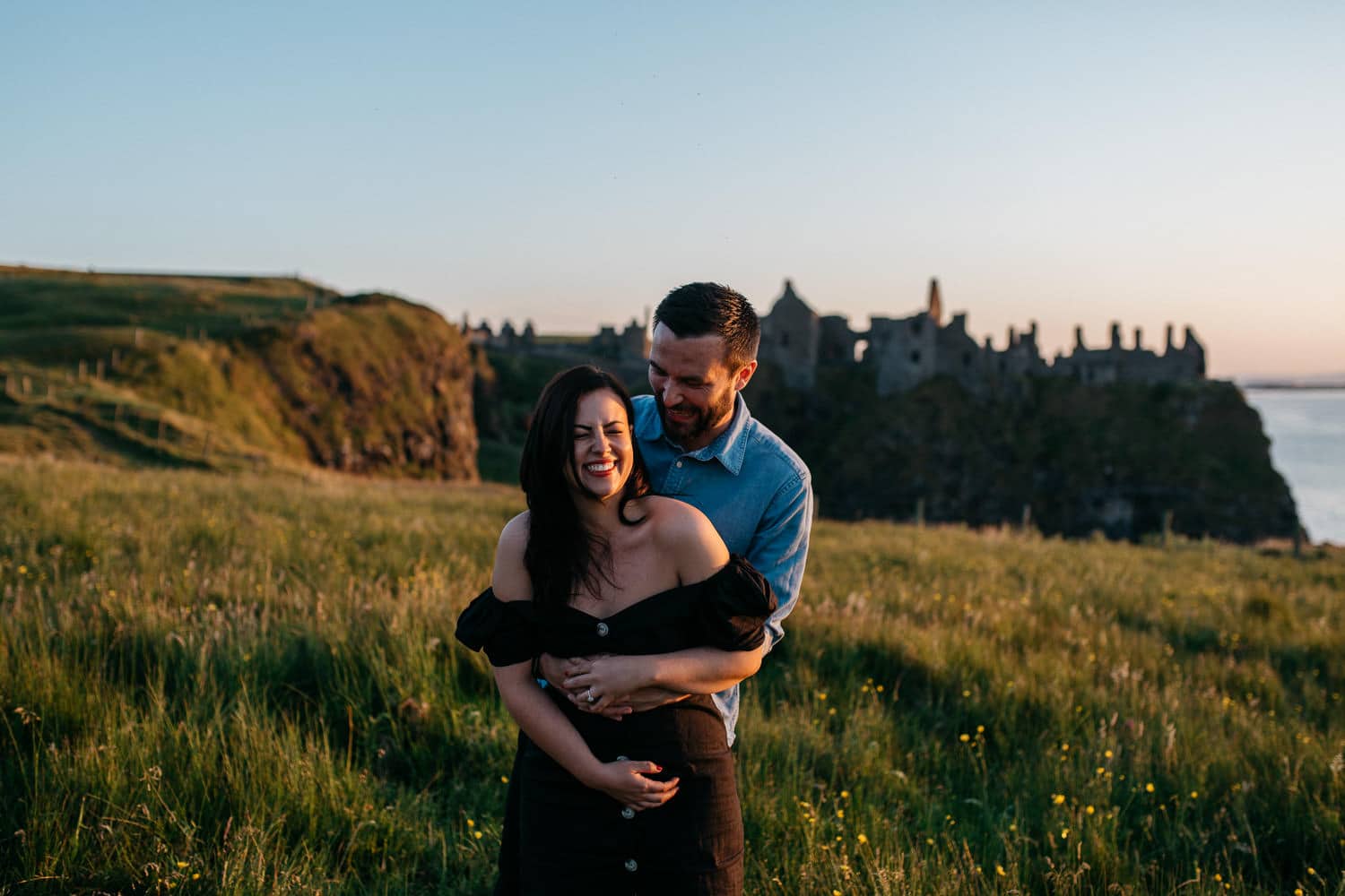 couple laughing in from of Dunluce Castle Engagement Photography Northern Ireland