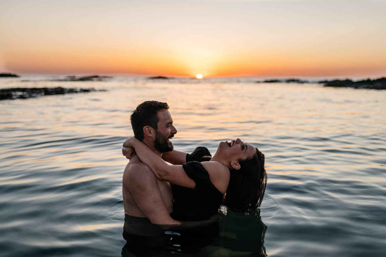 couple laughing in the water at sunset Engagement Photos Northern Ireland