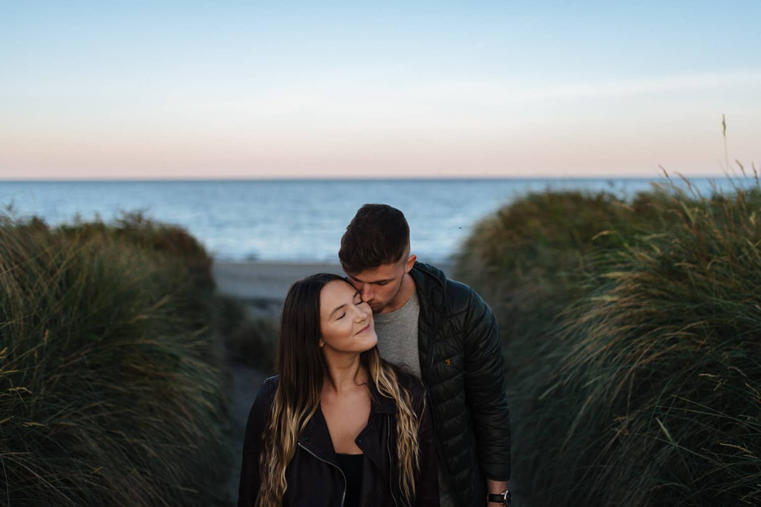 couple in front of the sea at sunset Belfast Engagement Photos