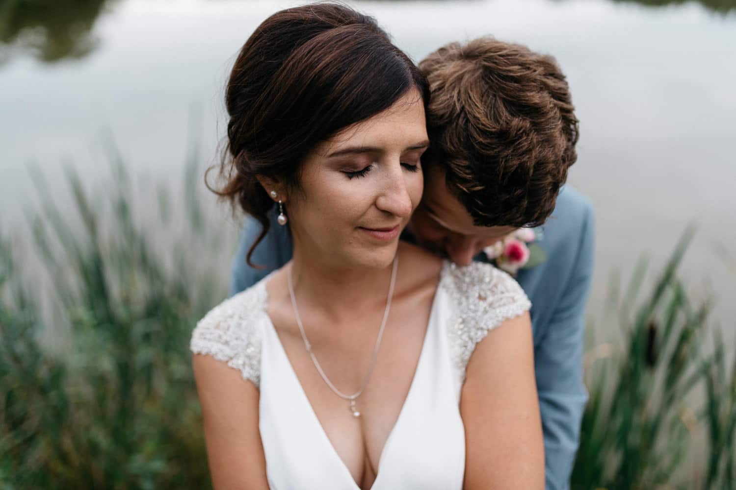 bride kissing grooms shoulder at the lake Lissanoure Castle Wedding Photography