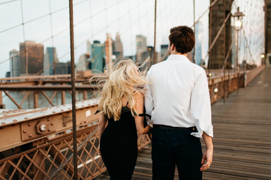 couple walking holding hands hair blowing in the wind New York Engagement
