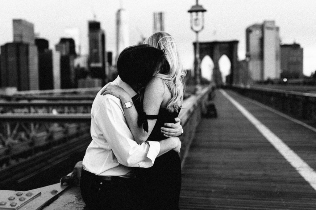 couple hugging on Brooklyn bridge Manhattan New York Engagement