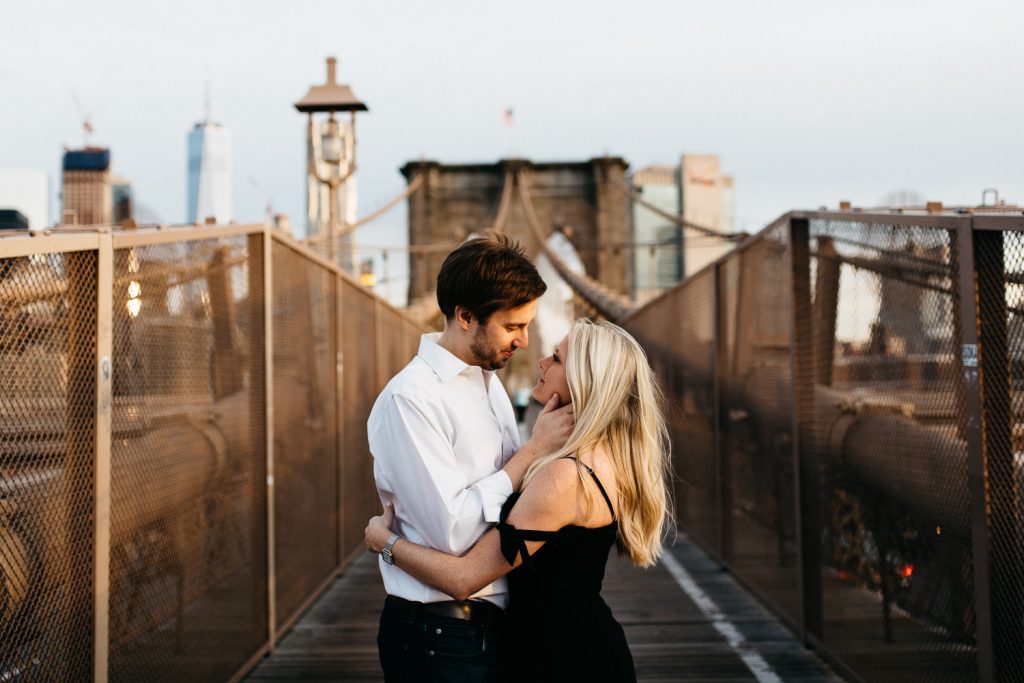 couple looking at each other in embrace on Brooklyn bridge New York Engagement
