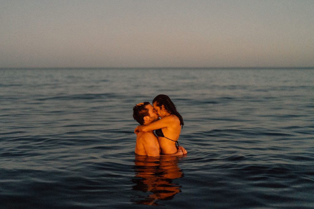 couple kissing in the water on their engagement shoot Barcelona Wedding Photographer