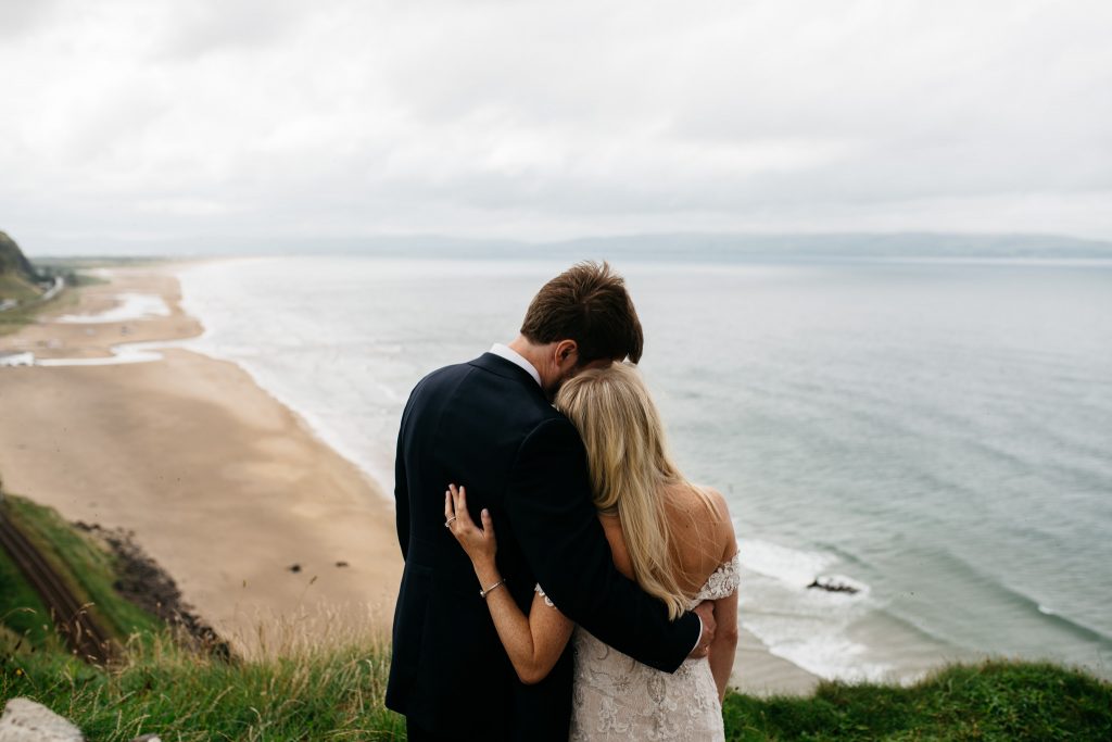 couple in embrace at Mussenden temple over looking the sea Northern Ireland Elopement Photographers