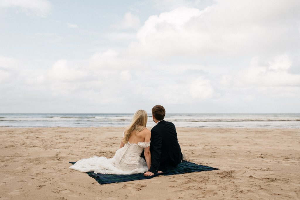 couple sitting on the beach looking off into the sea Northern Ireland Elopement Photographers