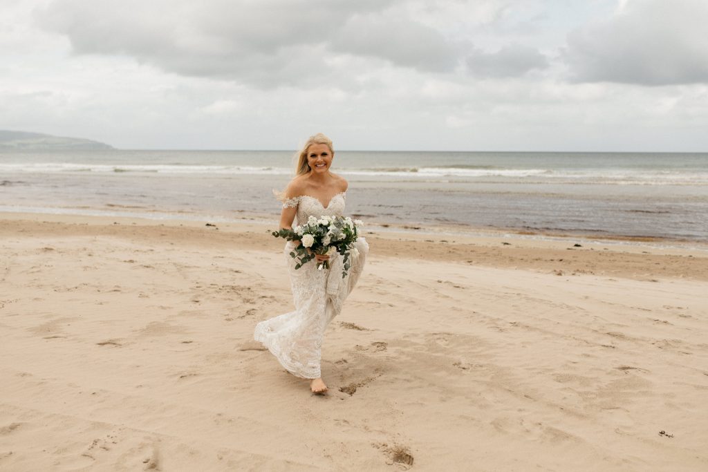bride walking on the beach with flowers Elopement Photographer Ireland
