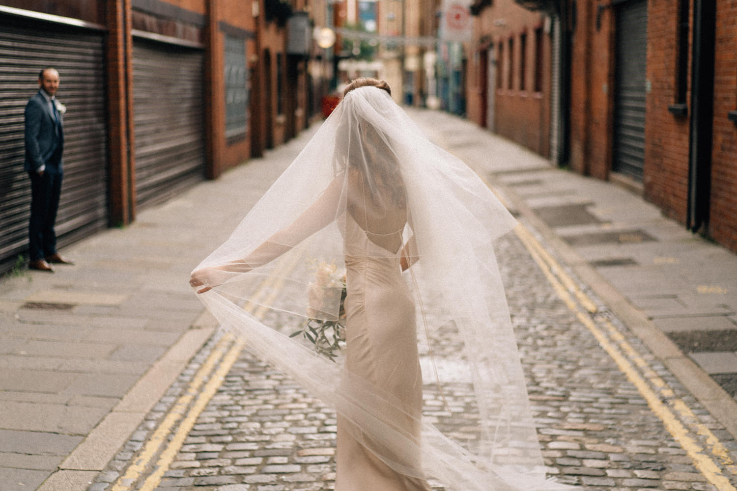 bride playing with veil on cobbled streets Belfast Merchant Hotel Belfast Wedding