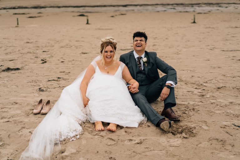 groom laughing wildy sitting on the beach Northern Ireland Elopement Photography