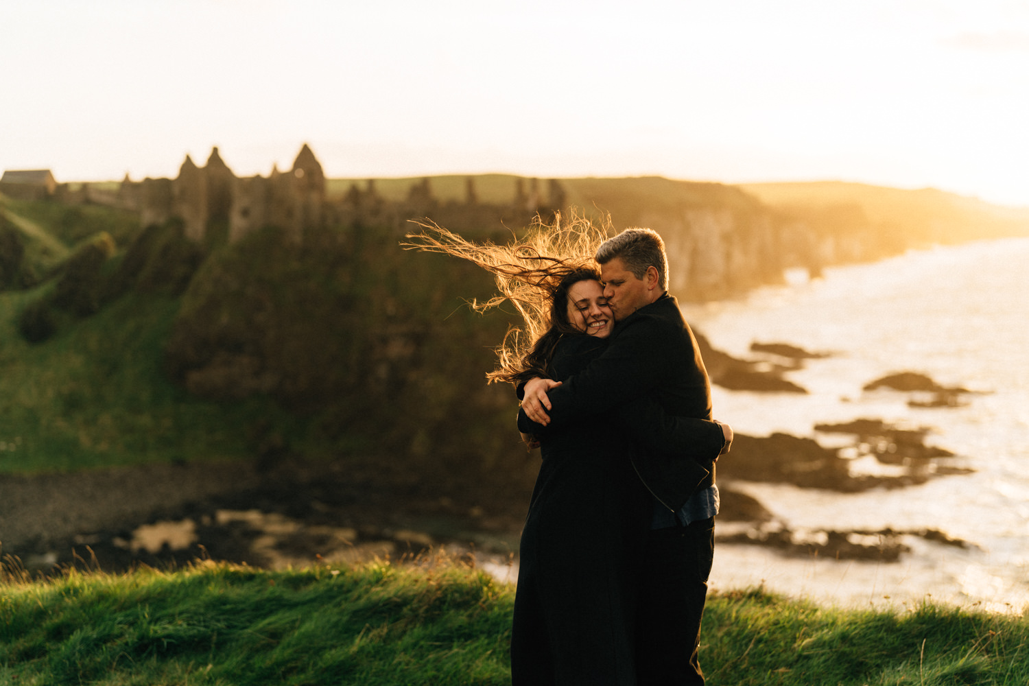 couple hugging at sunset overlooking Dunluce Castle  Elopement Photographer - Couples Photographer