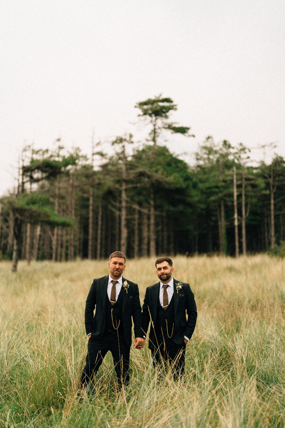 groom holing hands with groom in forest same sex wedding wedding photographers northern ireland