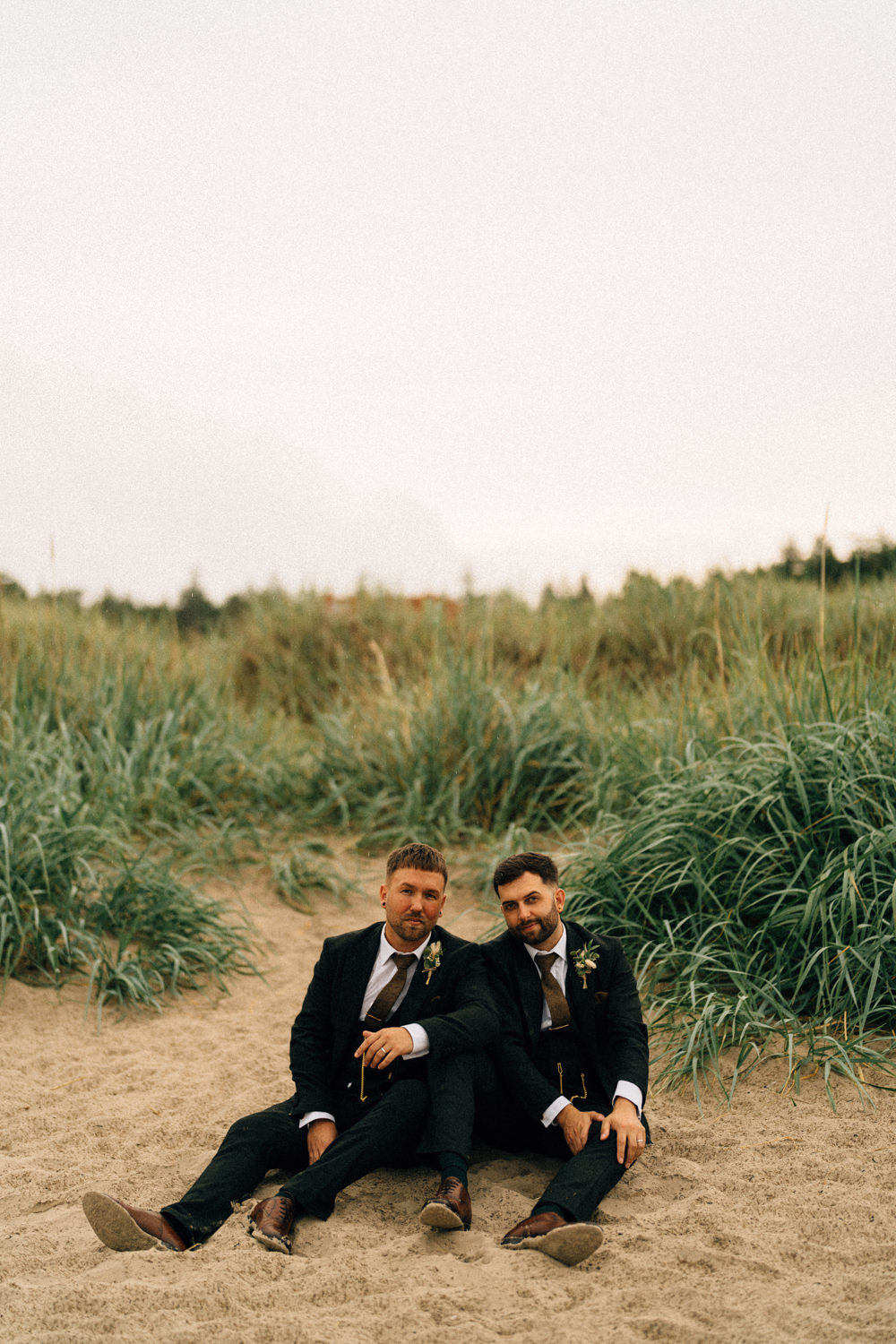 two grooms sitting on the beach same sex wedding wedding photographers northern ireland