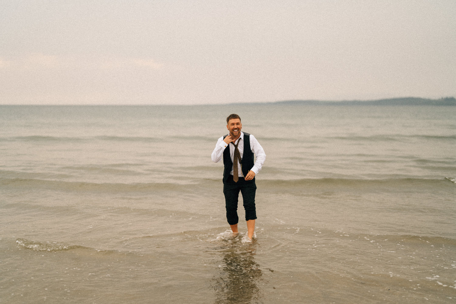 groom having fun in the sea same sex wedding wedding photographers northern ireland