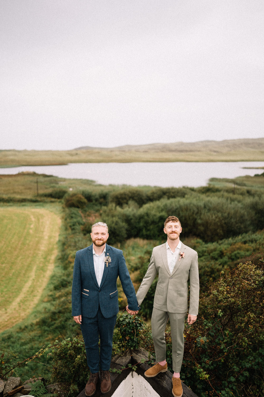 two grooms holding hands with lough in the background LGBTQ Wedding Photographer Ireland