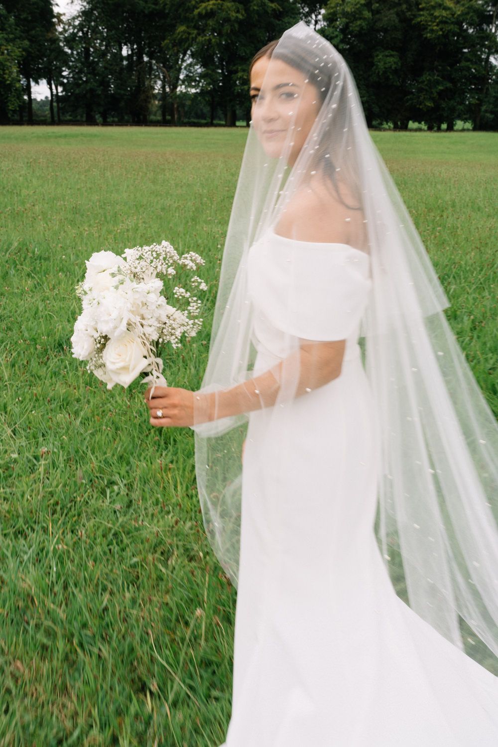 bride holding flowers in green field  tankardstown wedding