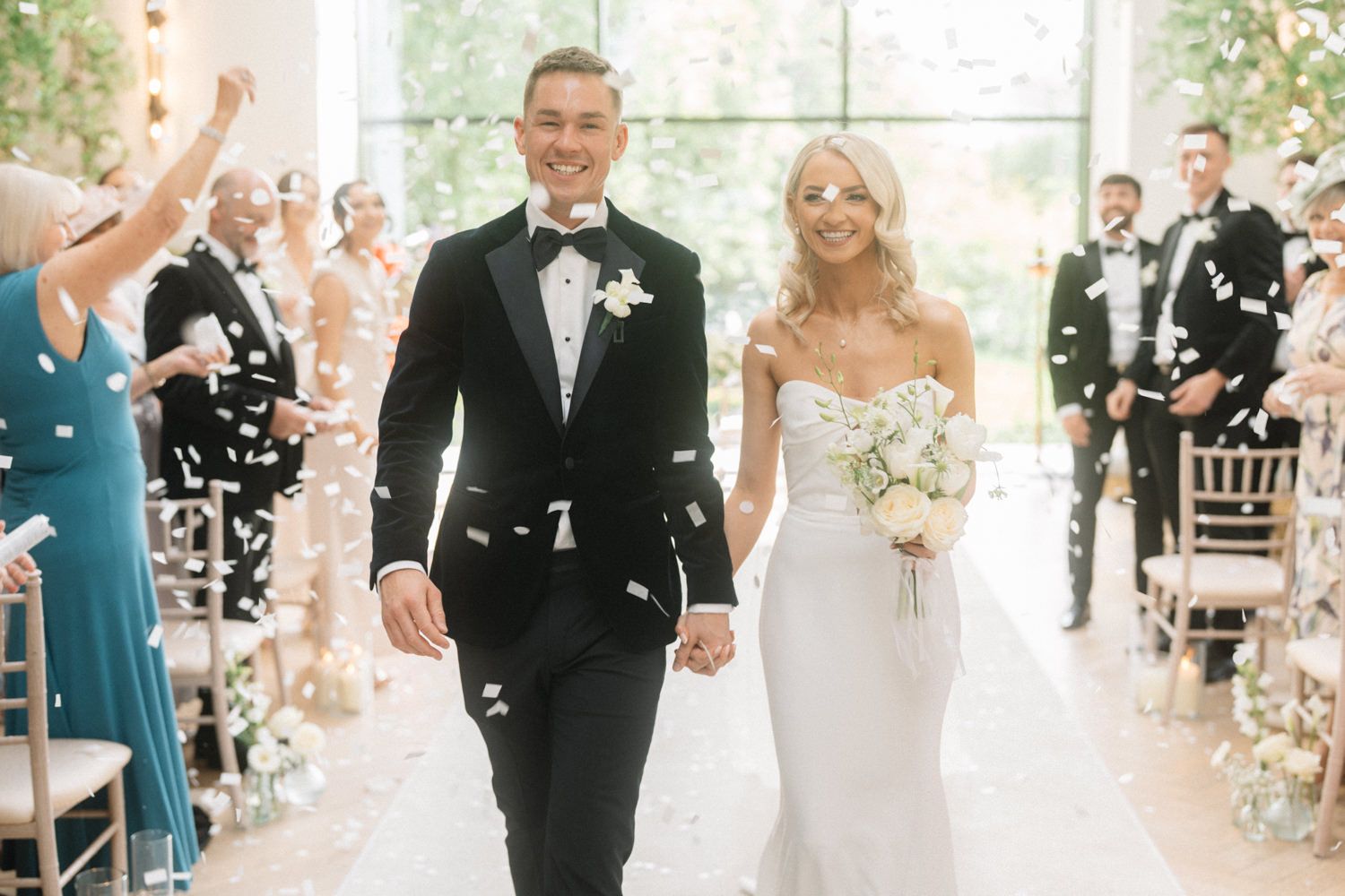 bride and groom walking down the isle with confetti Captured by a Cabra Castle Wedding Photographer