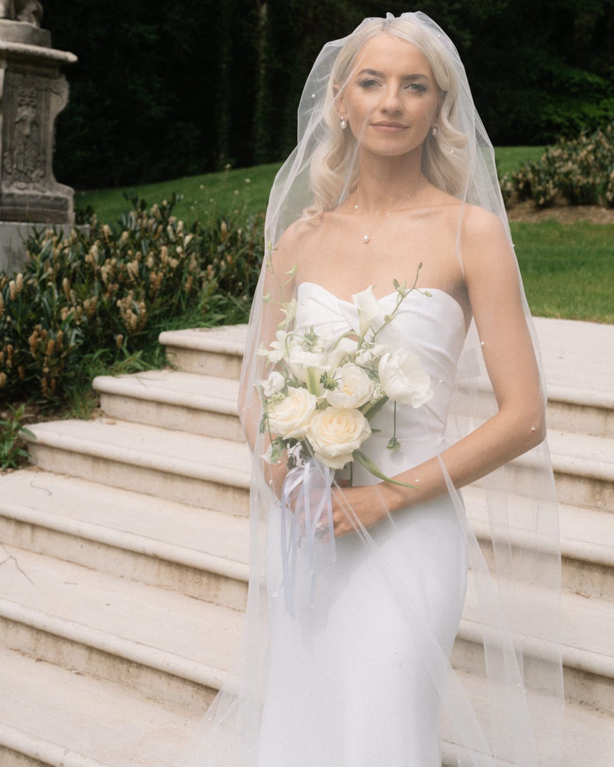 bride under the veil holing flowers at the steps CCabra Castle Wedding Photographer